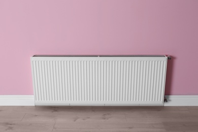 Photo of Modern radiator on color wall indoors. Central heating system