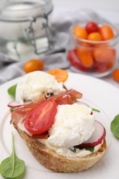 Photo of Delicious sandwich with burrata cheese, ham, radish and tomato on plate, closeup. Space for text