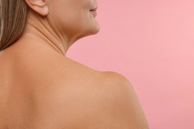 Photo of Mature woman with healthy skin on pink background, closeup. Space for text