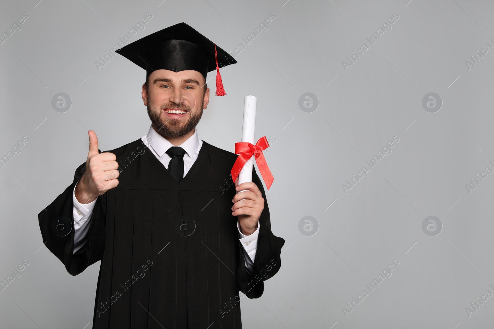 Photo of Happy student with graduation hat and diploma on grey background. Space for text