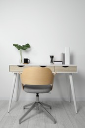 Comfortable workplace with white desk near wall indoors