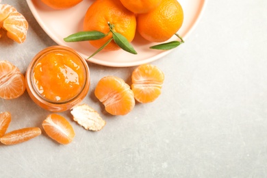 Photo of Flat lay composition with tasty tangerine jam on light grey table. Space for text