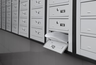 Photo of Open grey metal mailbox with envelopes indoors