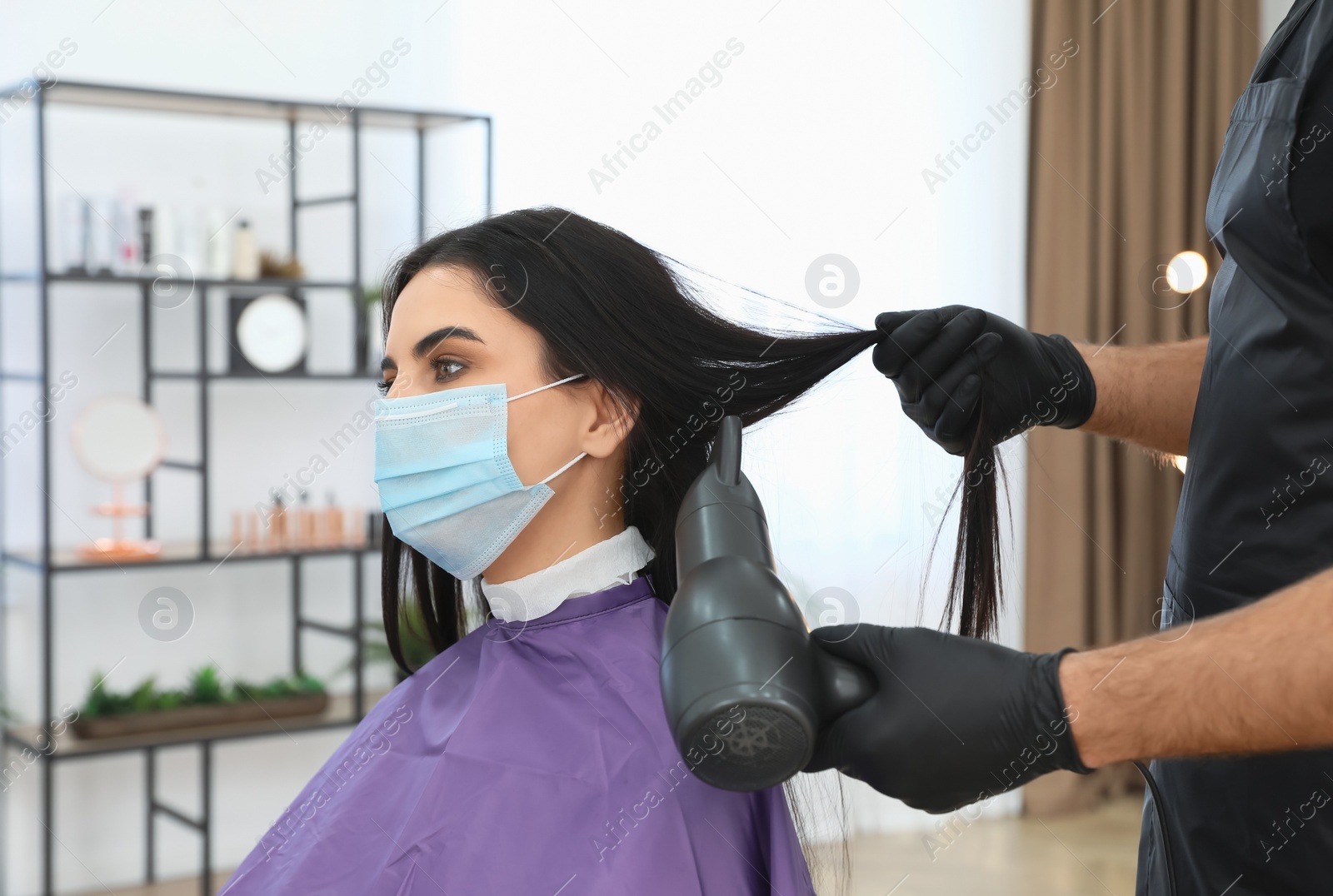 Photo of Professional stylist working with client in salon, closeup. Hairdressing services during Coronavirus quarantine