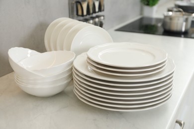 Clean plates and bowls on white marble countertop in kitchen