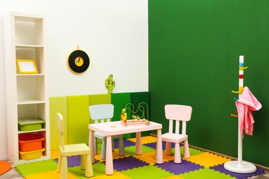 Photo of Stylish playroom interior with table and chairs