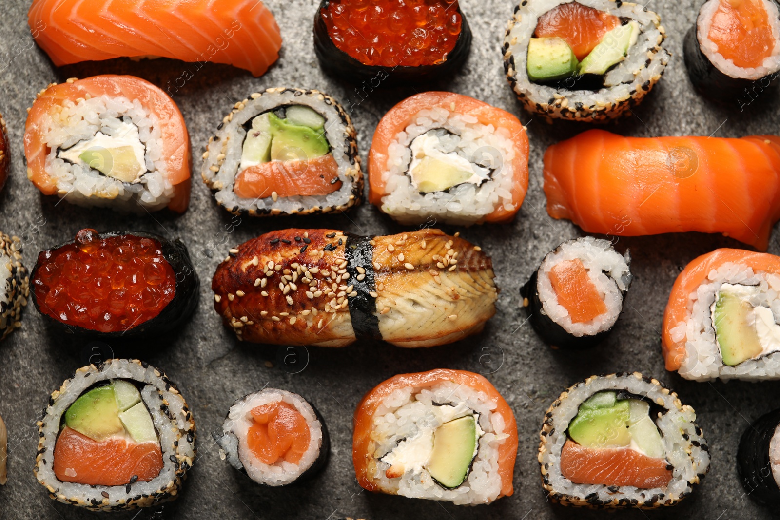 Photo of Different tasty sushi rolls on grey table, flat lay