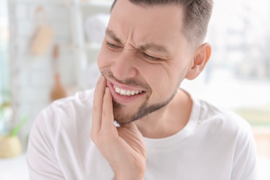 Young man suffering from toothache indoors