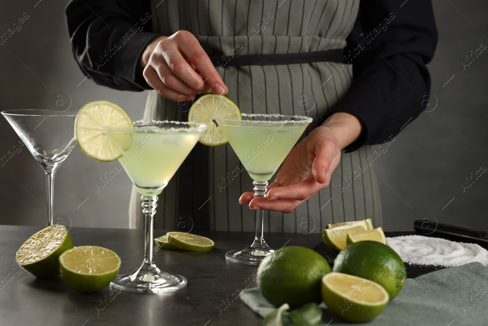 Photo of Woman making delicious Margarita cocktail at grey table, closeup