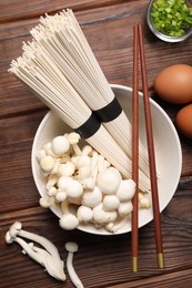 Photo of Cooking delicious ramen soup. Different ingredients and chopsticks on wooden table, flat lay