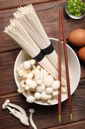 Cooking delicious ramen soup. Different ingredients and chopsticks on wooden table, flat lay