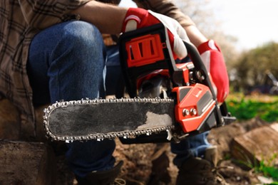 Photo of Man with modern electric saw outdoors, closeup