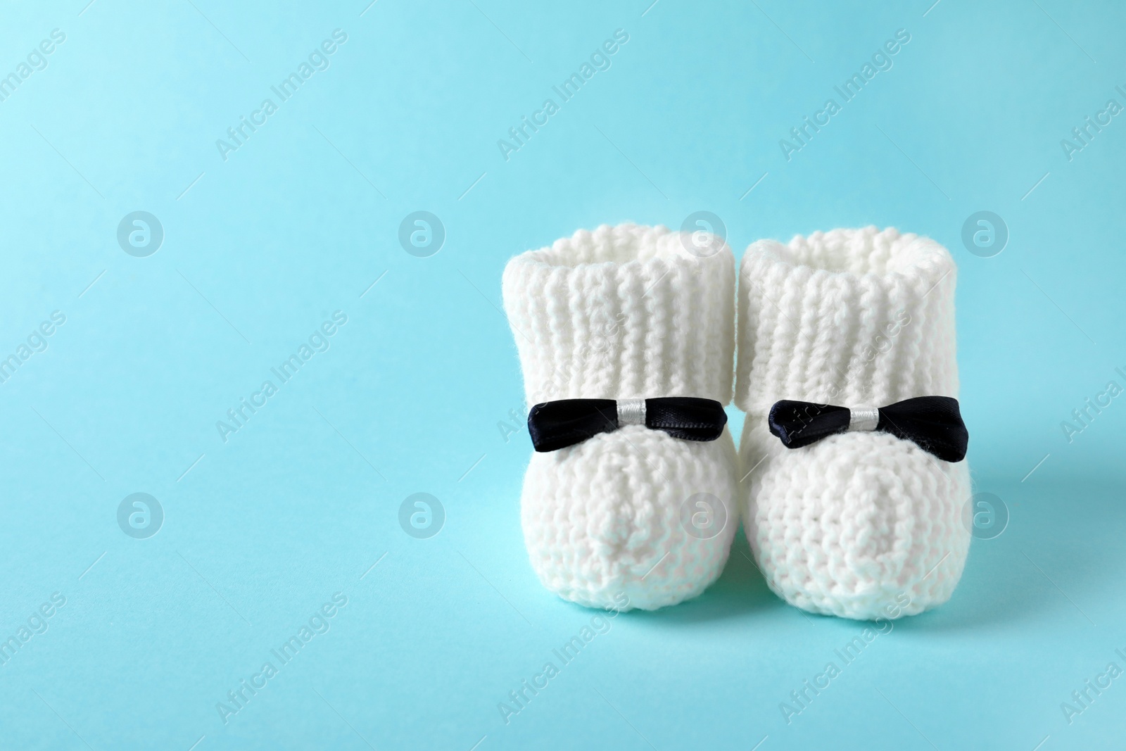 Photo of Handmade baby booties on color background. Space for text