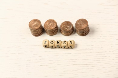 Photo of Word Forex with cubes and stacked coins on white wooden table, above view
