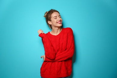 Beautiful young woman in warm sweater on color background