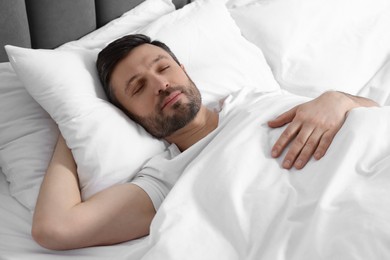 Photo of Handsome man sleeping in soft white bed