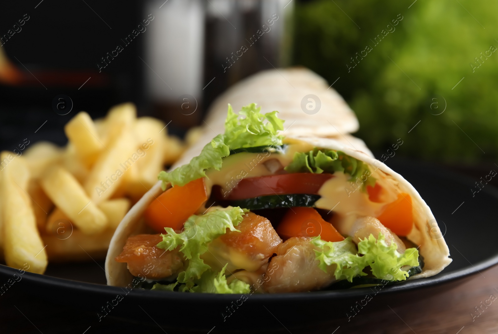 Photo of Delicious chicken shawarma and French fries on wooden table, closeup