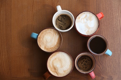 Photo of Cups of fresh aromatic coffee on wooden table, top view