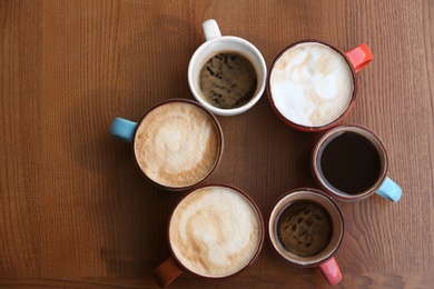 Cups of fresh aromatic coffee on wooden table, top view