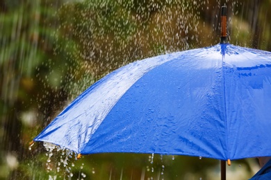 Photo of Bright umbrella under rain on street, closeup