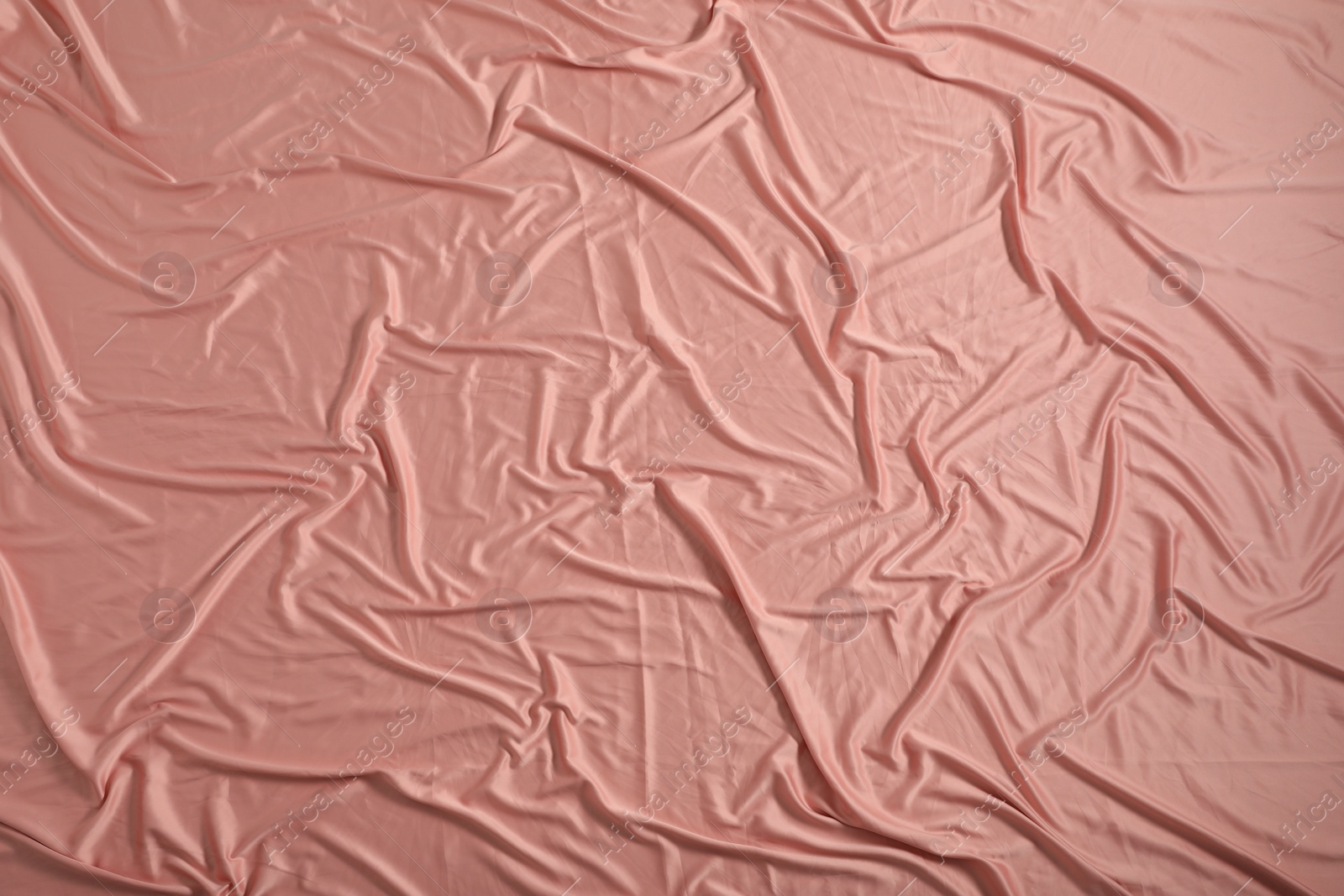 Photo of Crumpled coral fabric as background, closeup view