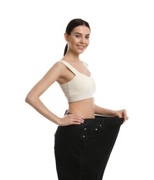 Photo of Happy young woman wearing big jeans after weight loss on white background