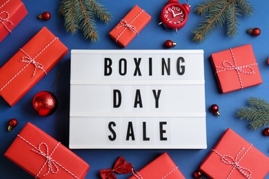 Lightbox with phrase BOXING DAY SALE and Christmas decorations on blue background, flat lay