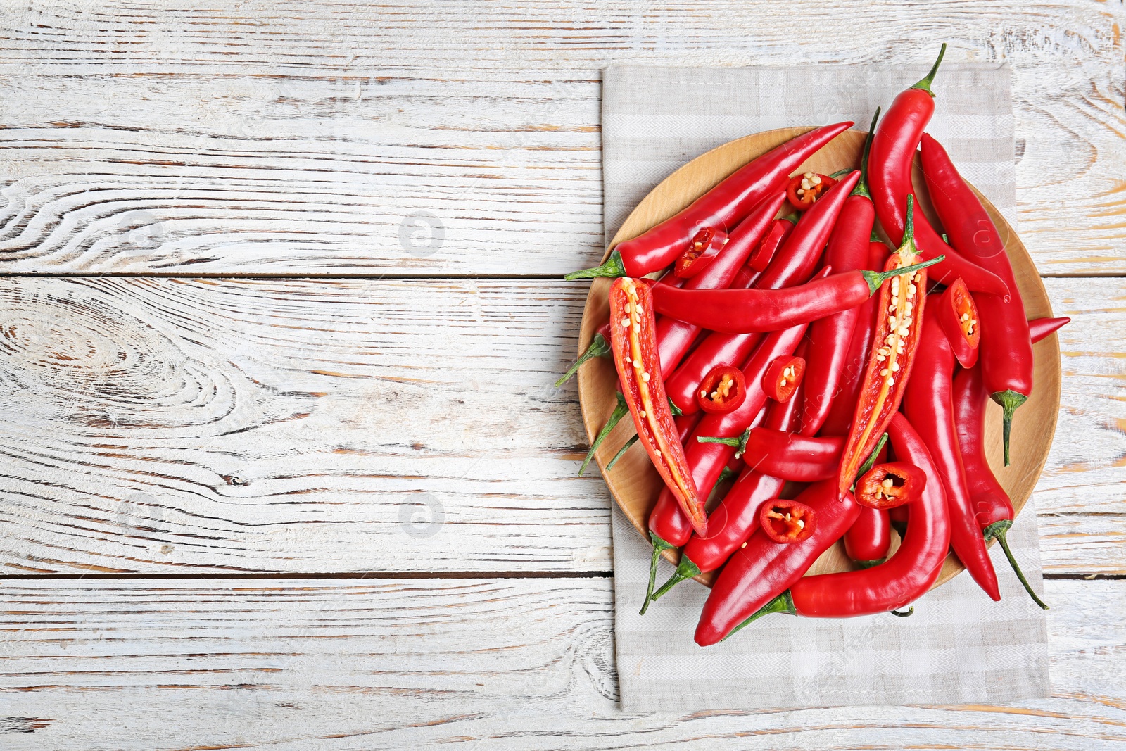 Photo of Plate with chili peppers on wooden background, top view