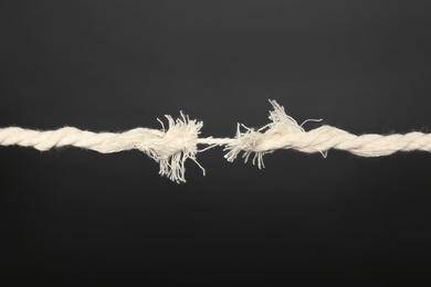 Frayed rope at breaking point on gray background