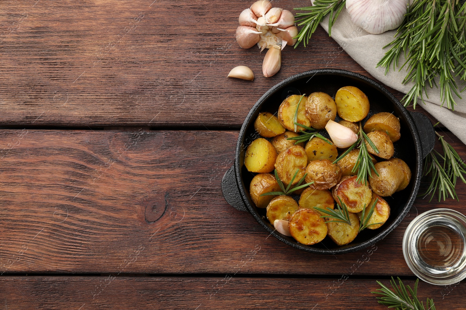 Photo of Delicious baked potatoes with rosemary and ingredients on wooden table, flat lay. Space for text