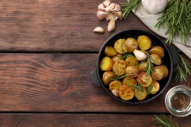 Photo of Delicious baked potatoes with rosemary and ingredients on wooden table, flat lay. Space for text