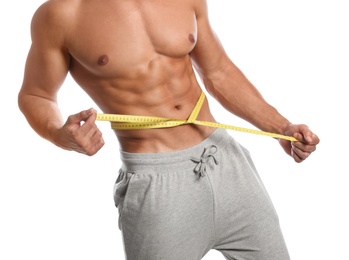 Young man with slim body using measuring tape on white background, closeup view