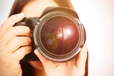 Image of Photographer with professional camera on light background, closeup