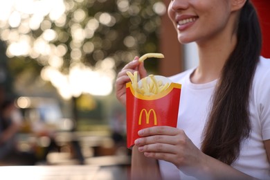 Photo of Lviv, Ukraine - September 26, 2023: Woman with McDonald's french fries outdoors, closeup. Space for text