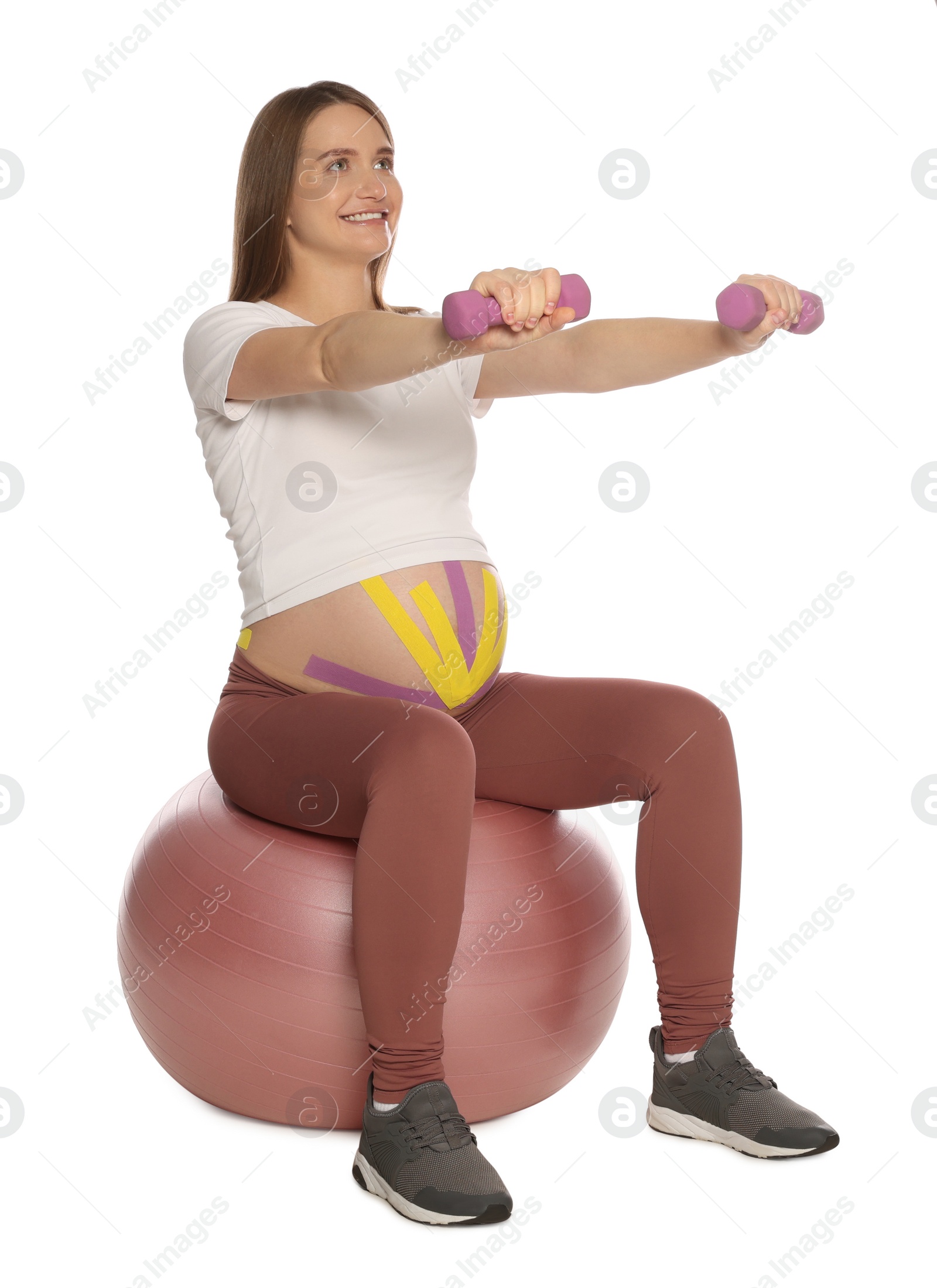 Photo of Sporty pregnant woman with kinesio tapes doing exercises on white background