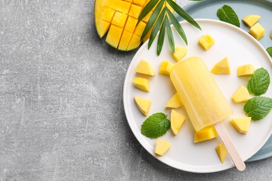 Photo of Plate of tasty fruit ice pop with mango on grey table, flat lay. Space for text