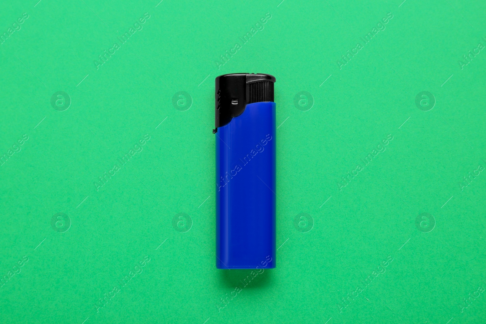 Photo of Stylish small pocket lighter on green background, top view