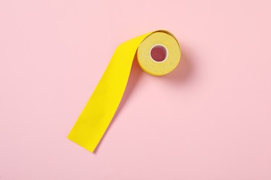 Photo of Bright kinesio tape in roll on pink background, top view