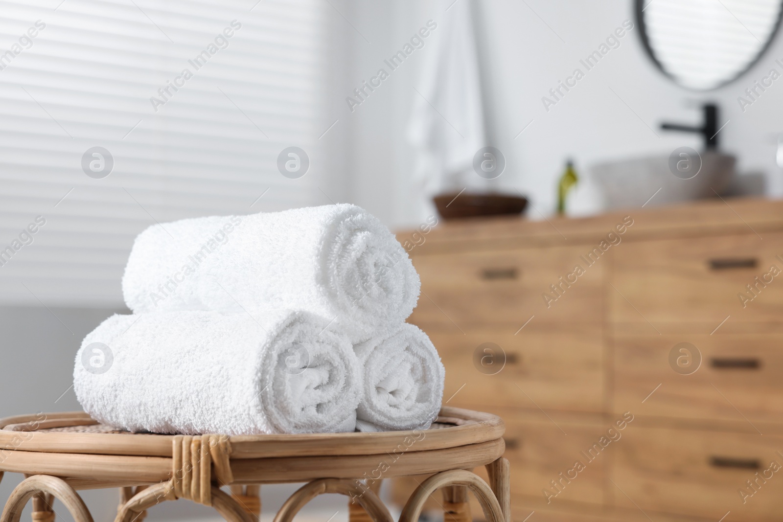 Photo of Rolled bath towels on wicker table in bathroom. Space for text