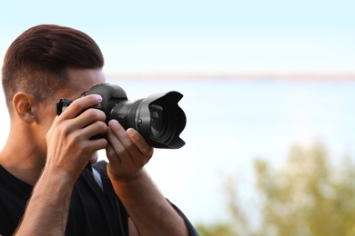 Photographer taking picture with professional camera near river