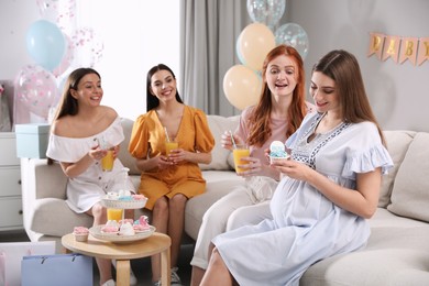 Happy pregnant woman spending time with friends at baby shower party