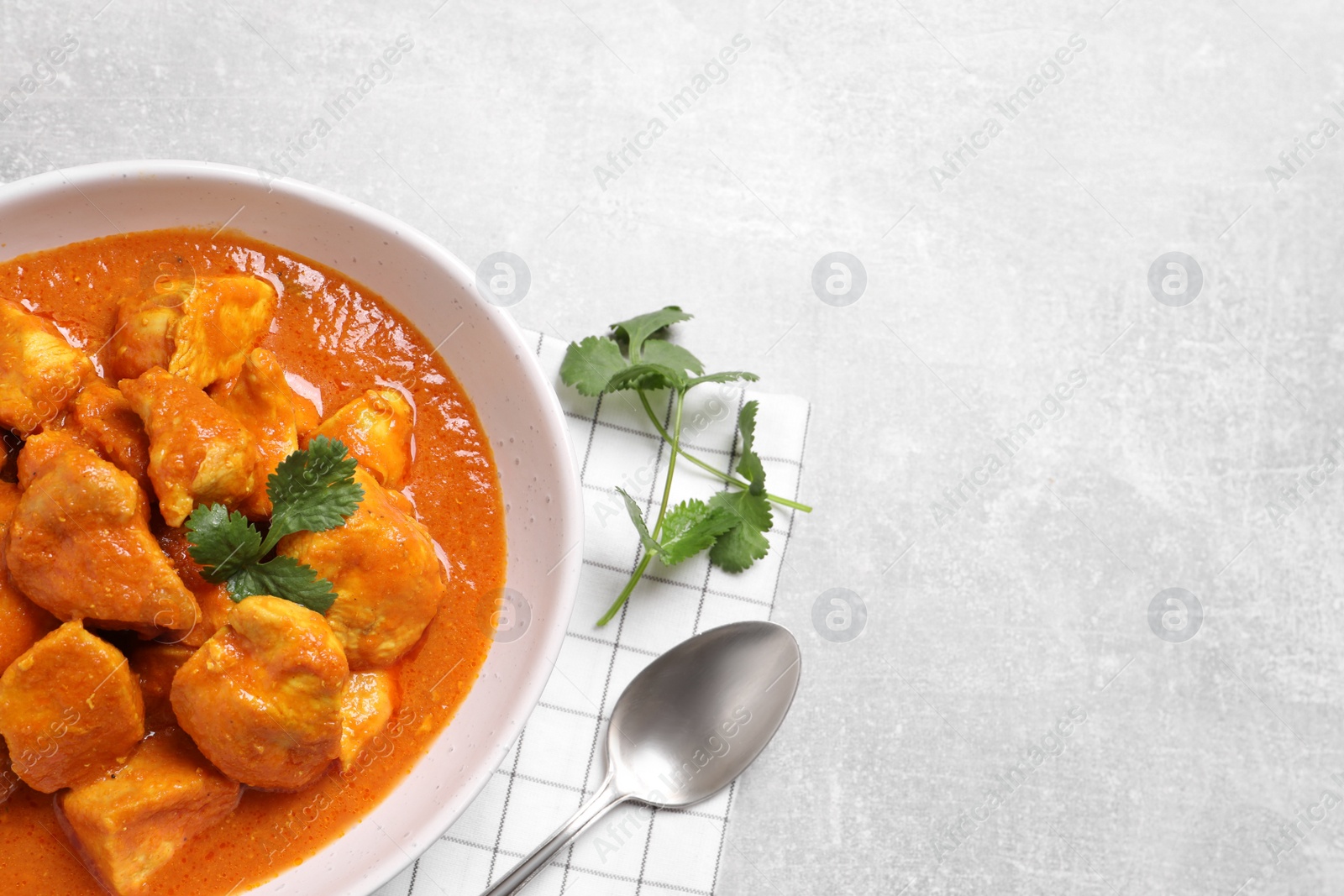 Photo of Bowl of delicious chicken curry on light grey table, top view. Space for text