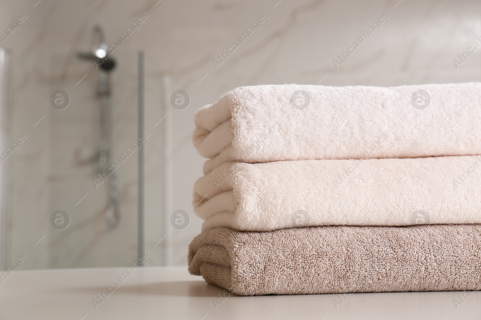 Photo of Stack of clean towels on table in bathroom, closeup. Space for text