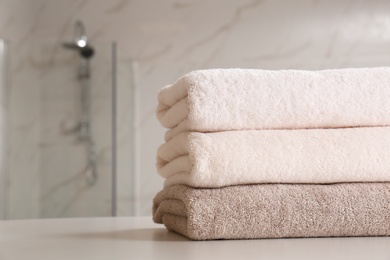 Stack of clean towels on table in bathroom, closeup. Space for text