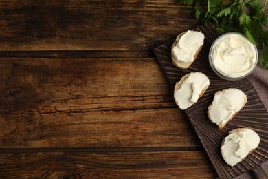 Bread with cream cheese on wooden table, flat lay. Space for text