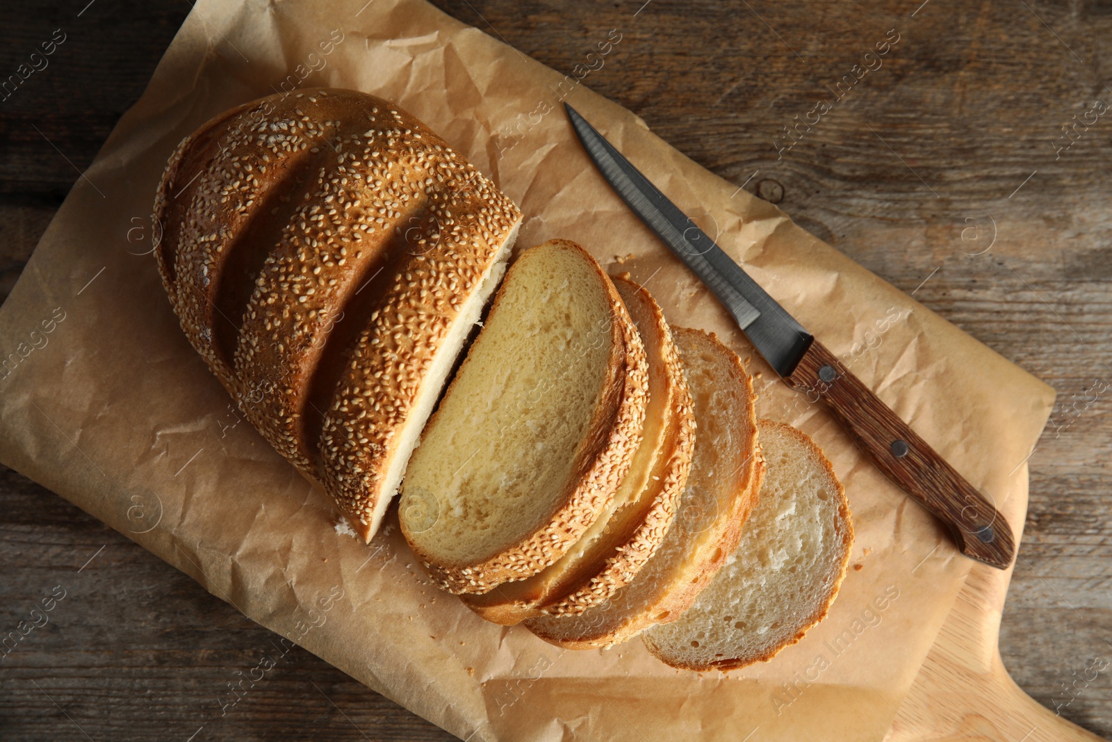 Photo of Board with tasty bread on wooden background, top view