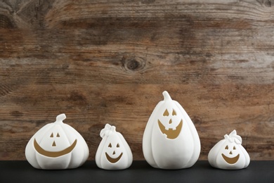 Jack-o-Lantern candle holders on black table against wooden background, space for text. Halloween decor