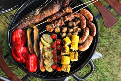 Photo of Tasty meat and vegetables on barbecue grill outdoors, top view