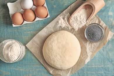 Raw dough with poppy seeds and ingredients on wooden table