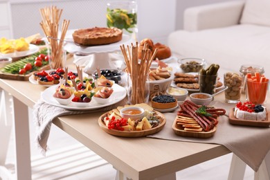 Dishes with different food on table in living room. Luxury brunch